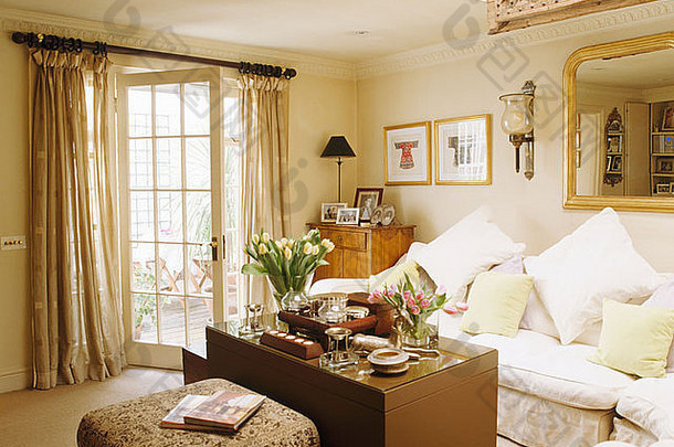 客厅里的奶油色沙发和大木箱用作咖啡桌，法式窗户上有米色亚麻<strong>窗帘</strong>