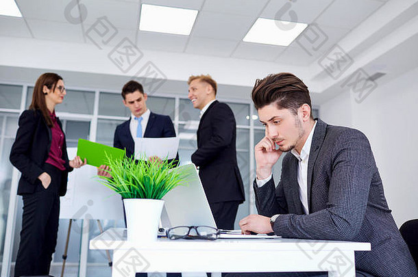商人在办公桌旁，在后台用笔记本电脑工作