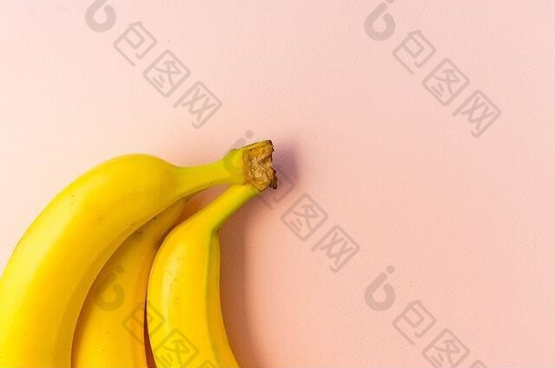 粉红色纸背景上的黄色成熟香蕉串，版面，水平位置