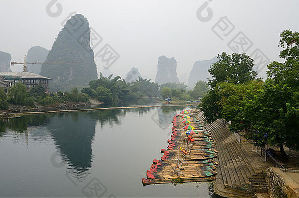 中华人民共和国玉龙江畔阳朔的一排竹筏旅游船和尖尖的喀斯特山峰