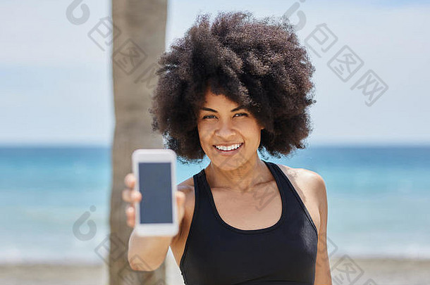 海滩上手持智能手机的快乐非裔美国女孩画像