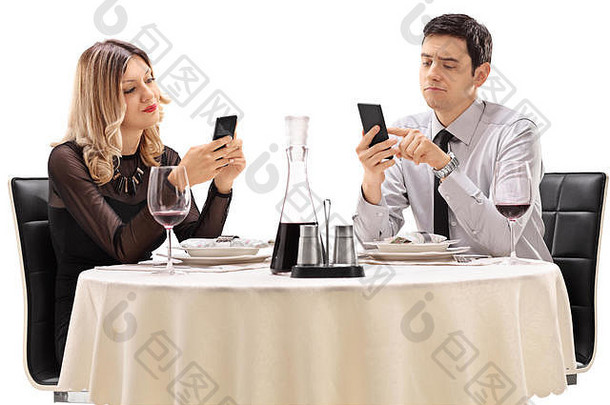 年轻的男人。女人坐着日期细胞手机孤立的白色背景