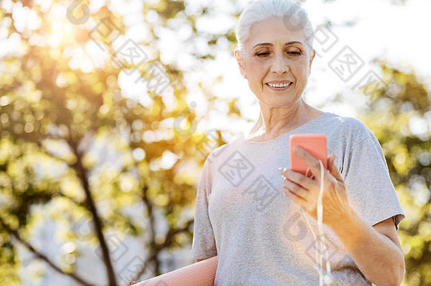 快乐的老妇人在公园里使用智能手机
