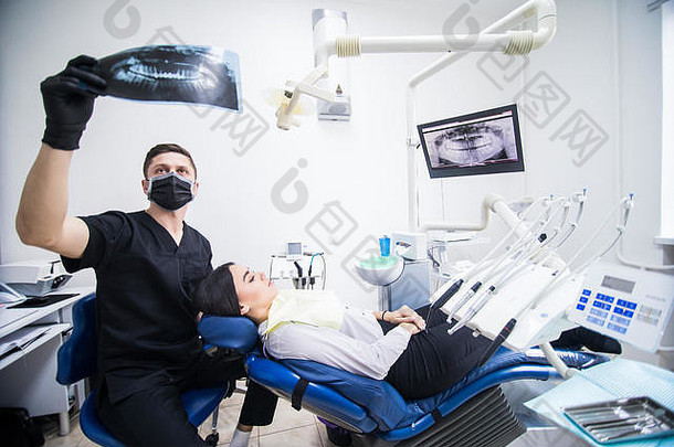 牙医在牙科诊所看年轻女病人的牙齿x光片