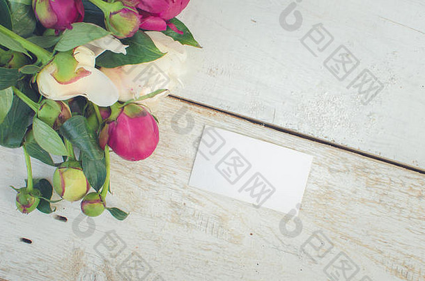 牡丹背景。白色木桌上有紫红色、粉色和白色的牡丹花，上面有一张空白的文字卡片。母亲节快乐。母亲节贺卡。五、