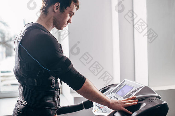 身穿黑色套装<strong>的</strong>男子在健身房跑步机上进行ems训练