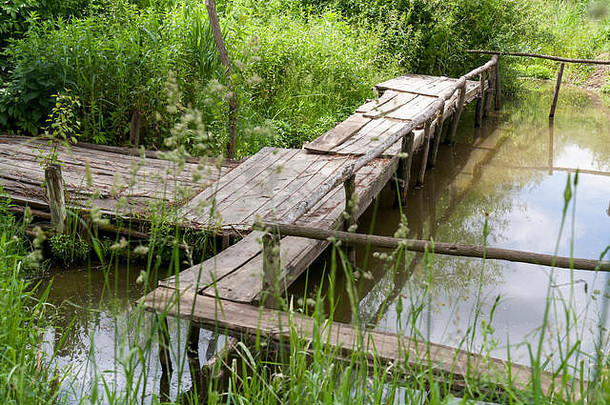 湖上长满了草的旧木桥。古老的乡村景观。