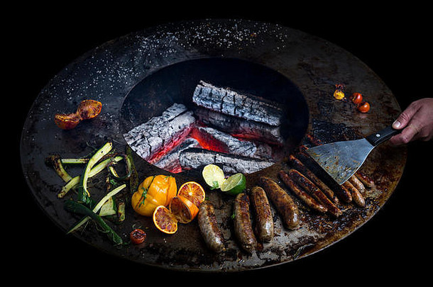 在火盆烤架上煮香肠。这个新概念-三位一体-结合了烹饪的优势，加上烤肉和火盆。