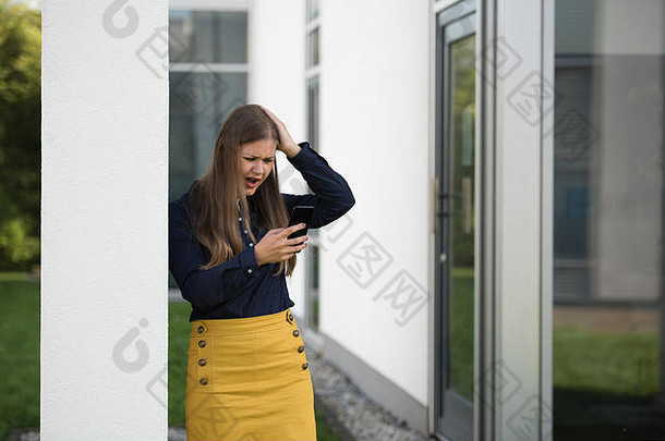 在办公楼前拿着智能手机解决问题的年轻女商人