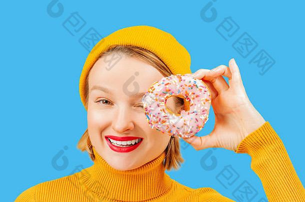 黄色背景下，滑稽女人的眼睛衬托着五颜六色的甜甜圈