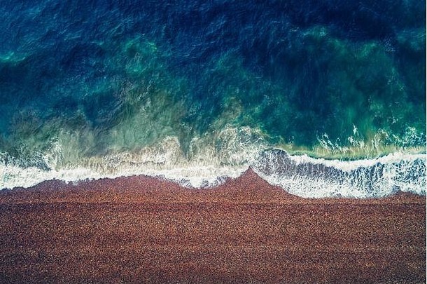 度假和旅游概念。卵石海滩自然背景的航空图像。照相机看起来很直。