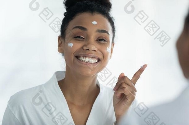 非洲妇女在脸上涂抹护肤霜，关心皮肤美容