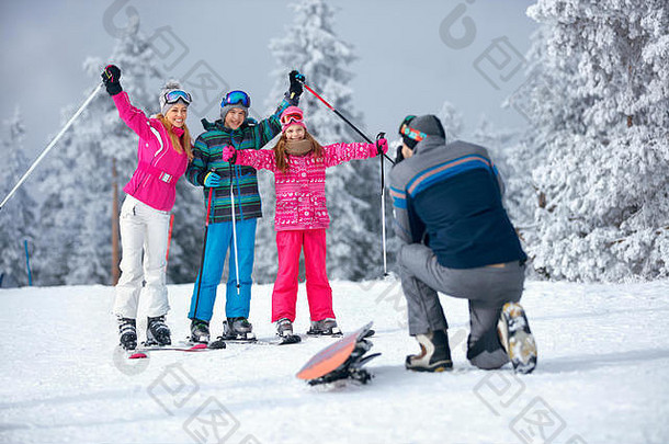 父亲在山上滑雪度假时给幸福的一家人拍照