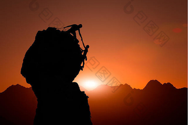 在日落时分，一队登山队员在一个奇妙的山景中攀爬，团队合作，帮助他们征服了顶峰