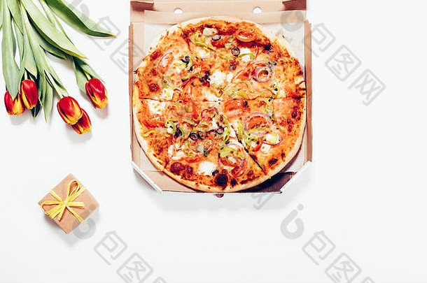 披萨盒，红色郁金香和一个<strong>小礼品</strong>盒放在白色的桌子上，俯视图