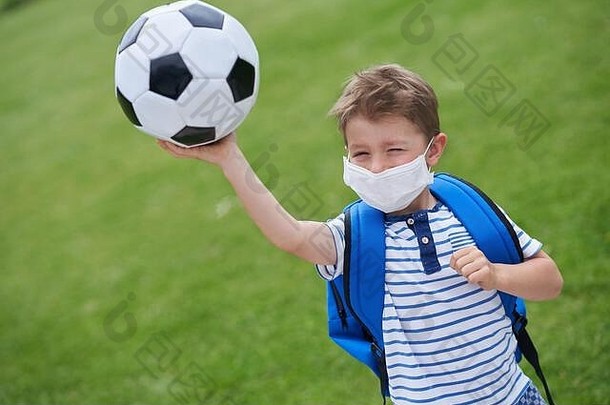 球场上戴着足球和防护面具的可爱小男孩