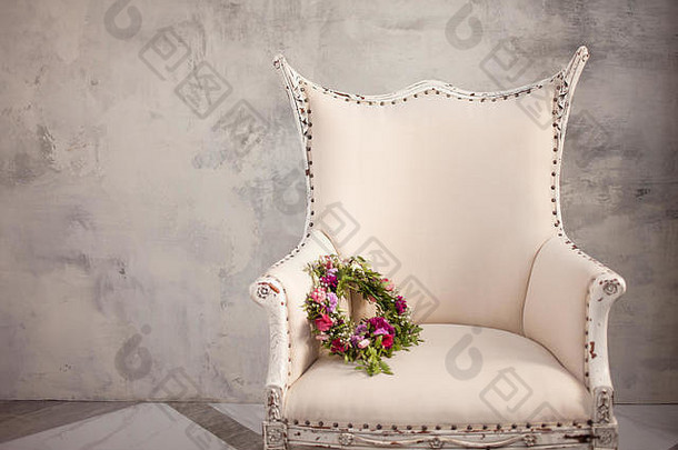 放在优雅的奶油色椅子上的鲜红色鲜花的婚礼花环。剩余的可用空间。
