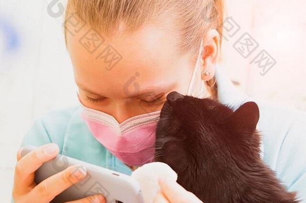 一个戴着医用口罩的女孩在家里与一只黑猫交流。
