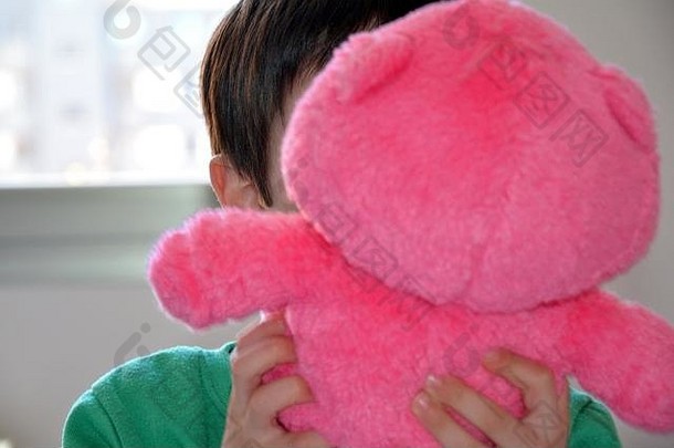 一个孩子带着他的粉色泰迪熊