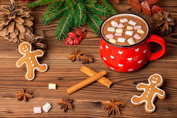 热巧克力配棉花糖糖果，木制背景上的姜饼饼干装饰圣诞树枝，甜筒和茴香，贺卡