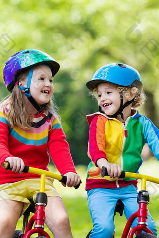 孩子们骑平衡自行车。孩子们在阳光公园骑自行车。在温暖的夏日，小女孩和男孩骑着滑翔机自行车。学龄前儿童学习平衡
