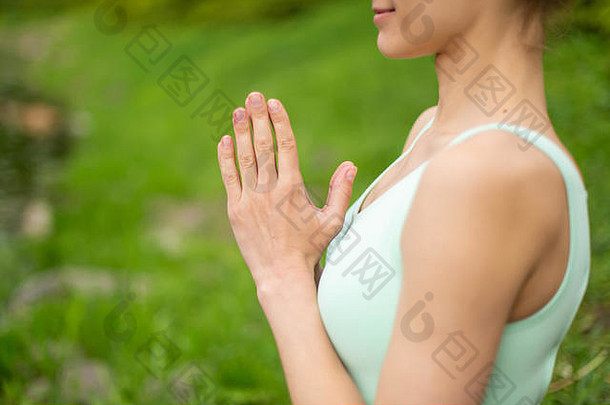 苗条的黑发女孩在一个夏季公园里做运动，做美丽而复杂的瑜伽姿势。背景是绿色的森林和河流。沃