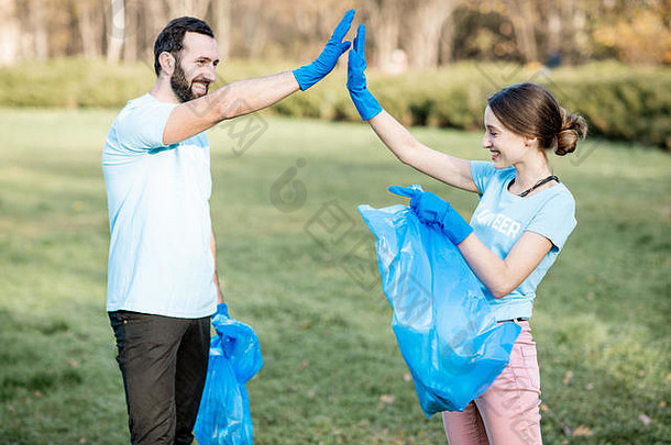 肖像快乐志愿者蓝色的t恤给手站袋完整的垃圾公园清洁