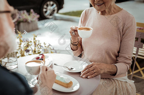 快乐的老妇人喝着美味的卡布奇诺