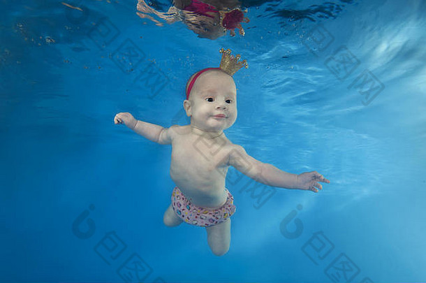 一个戴皇<strong>冠</strong>的小女孩在游泳池里游泳