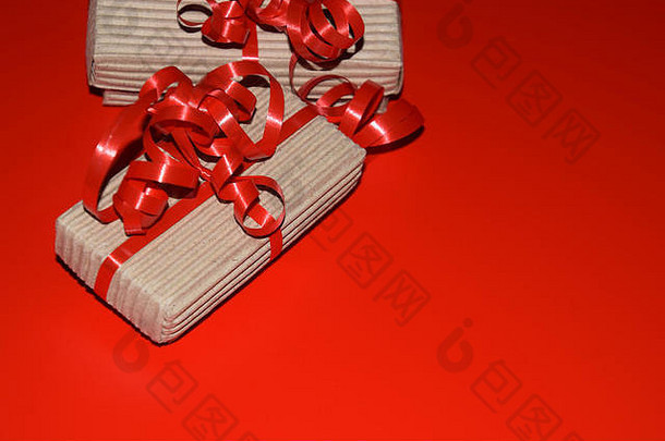 圣诞节背景，带有复印空间，礼品盒的俯视图用纸板包装，红色表面上有红丝带
