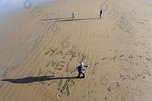 英国克利夫兰索尔特伯恩海滩，祖母和孙子孙女们在沙滩上写下新年快乐的祝福语