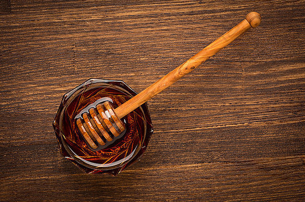 新鲜天然蜂蜜装在一个罐子里，蜂蜜勺放在木制乡村复古背景上
