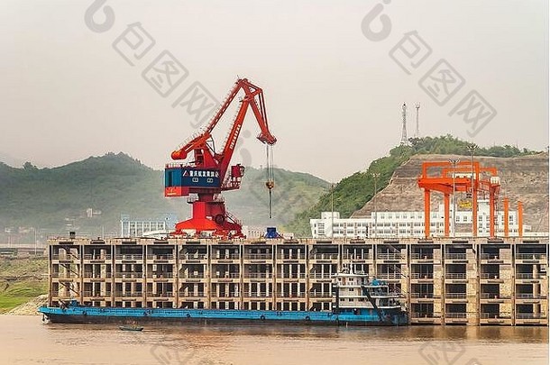 中国重庆黄岐口——2010年5月8日：长江。红色和蓝色起重机在港口多级码头卸载蓝色驳船。烟雾笼罩下的青山