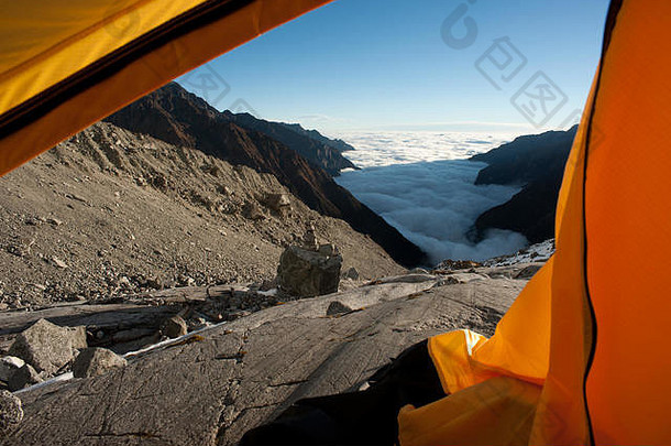 在附近的四川西部大雪山脉的明亚-康卡山体，阳光明媚的日子里，从云谷上的黄色帐篷向外看。中国