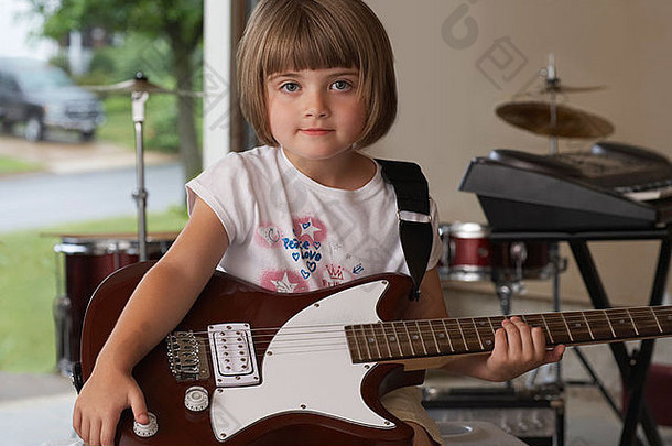 女孩（5-6岁）拿着吉他坐在车库里