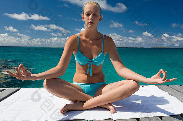 一位年轻女子在一个豪华的热带<strong>度假</strong>胜地做瑜伽姿势