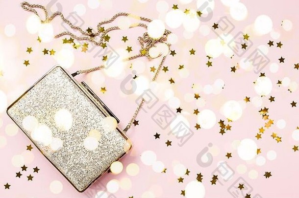 喜庆的傍晚金色手包，粉红色上点缀着星星。节日和庆典背景。豪华配件和派对理念。水平、粗体浅背景