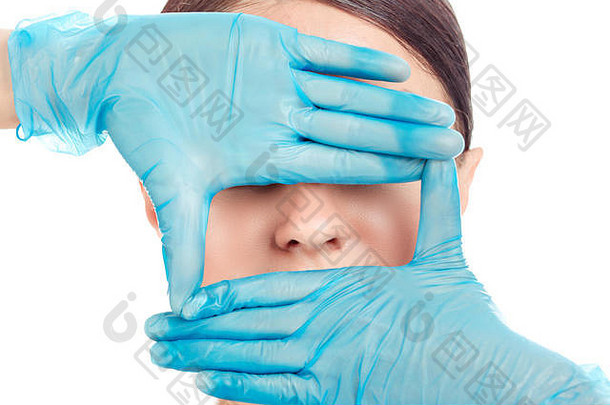 医生的手戴着手套围在一个女孩的鼻子上。这位妇女正准备做鼻子手术，在白色背景上做一个单独的切口。拉丁美洲混血儿