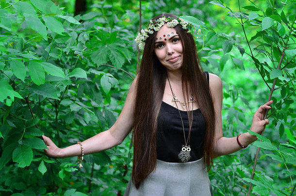 这是一张森林里的照片，照片上是一位美丽的年轻黑发女子，长着深褐色的眼睛和大大的嘴唇。女孩头上戴着花环