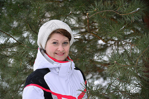 穿运动夹克戴帽子的女人在冬季松林