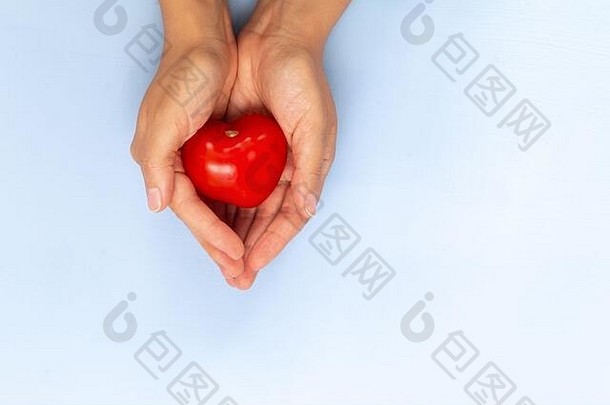 红色的小西红柿在手上呈心形，背景为淡蓝色，空白处为文本