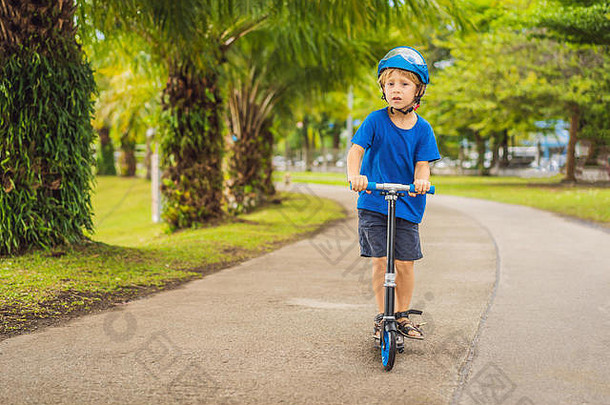 男孩骑着滑板车，在公园的户外，夏天。孩子们在户外玩得很开心。