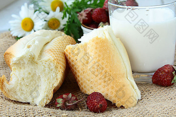 乡村早餐，白面包，牛奶和草莓放在亚麻袋上