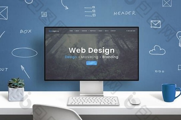 现代计算机显示器上的Web design studio主页。墙上有网页设计元素图纸的办公桌