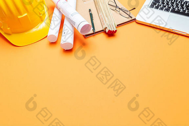 建筑工程师施工现场办公桌。项目蓝图，黄色安全帽和橙色笔记本电脑，复印空间