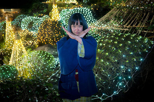 美丽的年轻女子在一个由灯光照亮的日本花园里摆姿势。