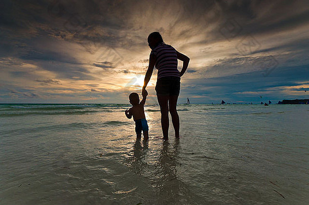 热带海滩<strong>日</strong>落时母亲和婴儿的剪影