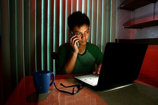 青少年在笔记本电脑前使用手机或智能手机