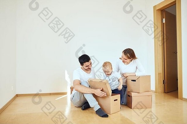 一家人带着小男孩在新家打开移动的纸箱