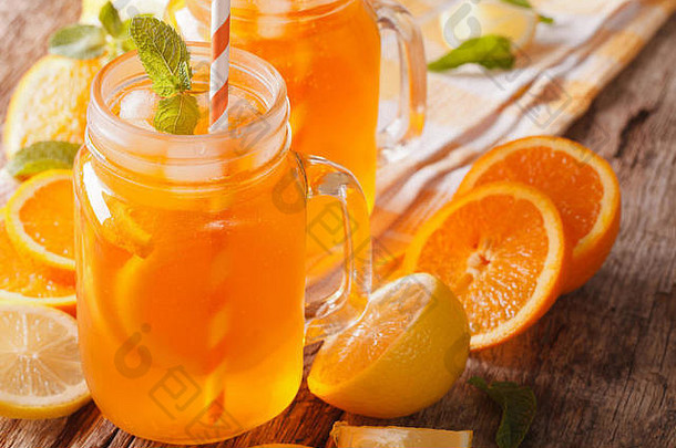 桌上的玻璃罐特写镜头里放着新鲜的鸡尾酒，里面有橙子、柠檬、冰块和薄荷。水平的